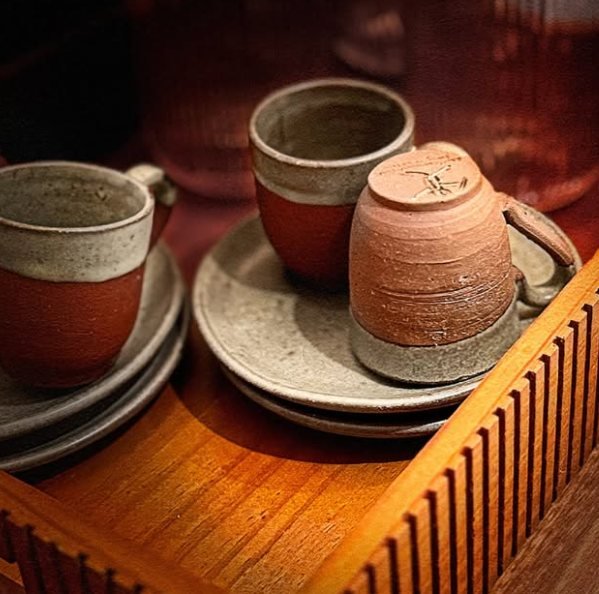 Xícaras de cerâmica artesanal sobre bandeja de madeira na recepção